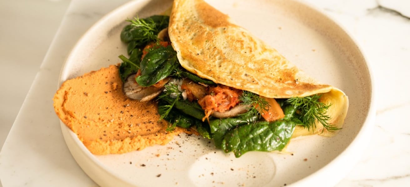 Omelette with meat and veggies on a plate on a white table